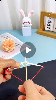 a person is holding a toothpick in front of an origami rabbit