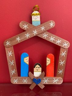 a wooden nativity scene with three people in the manger, on a red background