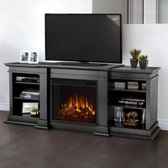 a flat screen tv sitting on top of a black entertainment center next to a fire place