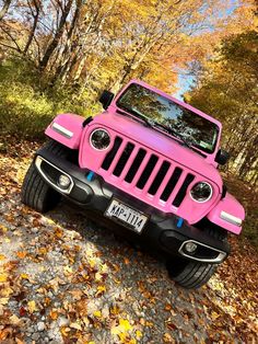 a pink jeep is parked in the leaves