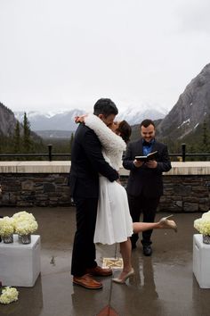 a bride and groom kiss as they stand in the rain