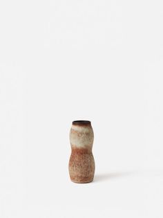 a small brown and white vase sitting on top of a table next to a wall