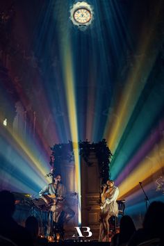 two people are performing on stage with colorful lights