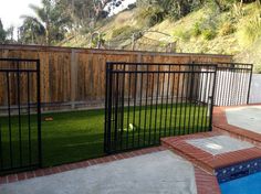 a fenced in backyard with a swimming pool and artificial grass on the side walk