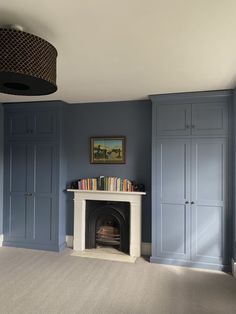 a living room with blue painted walls and a fire place in the center, along with built - in bookshelves