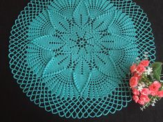 a crocheted doily with pink flowers on it and a small bouquet of red roses