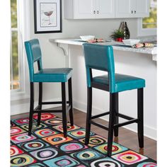 two blue bar stools sitting on top of a rug in front of a counter