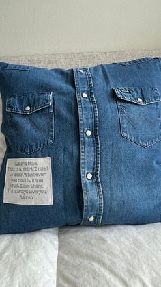 a blue jean pillow with a label on the front and back of it sitting on a bed