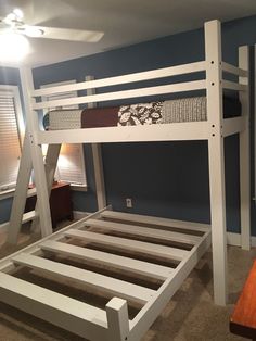 a white bunk bed sitting in a bedroom next to a wooden table