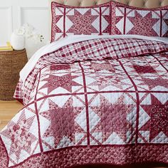 a red and white quilted bedspread on a bed in a room with hardwood floors