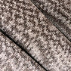 a close up shot of a brown and white herringbone tweed fabric with black stitching