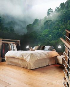 a bed room with a neatly made bed next to a wallpapered forest scene