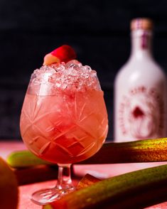 a pink drink sitting on top of a table next to bottles