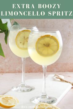 two glasses filled with lemonade sitting on top of a white tray next to sliced lemons