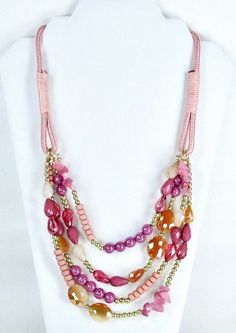 Pink multi strand four row necklace has a mix of genuine glass, stone and acrylic beads on a pink satin cord.  Necklace has    various shades of pink, tangerine, and  gold tone beads and stones.  Graduated overall length is 22".  Necklace has a lobster  claw clasp for closure with a 3" gold tone chain extension.  Gorgeous necklace for Society, and Pink - Red Hat ladies.   Excellent quality. Item #318P Red Hat Ladies, Statement Bib Necklace, Red Hat, Bib Necklace, Red Hats, Cord Necklace, Pink Stone, Fashion Jewelry Necklaces, Gorgeous Necklaces