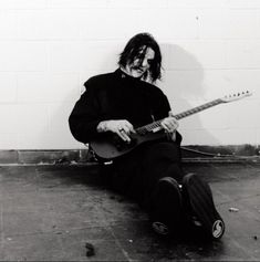 a man sitting on the ground playing a guitar