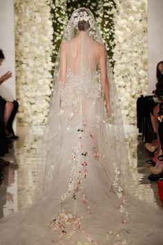 a model walks down the runway in a wedding dress with flowers all over her back