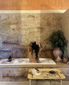 a woman sitting in a bathtub with her back to the camera