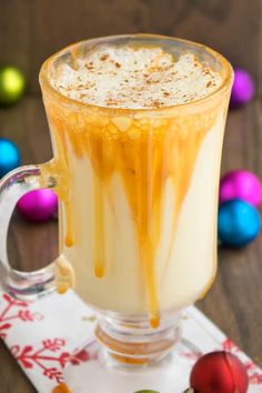 a glass mug filled with liquid sitting on top of a table next to colorful eggs