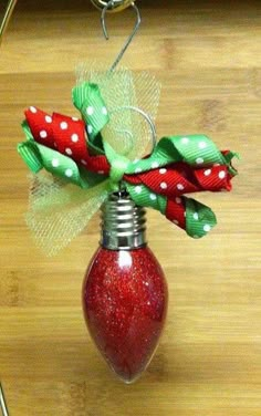 a red light bulb hanging from a wire on a wooden table with polka dot ribbon