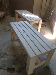 two wooden benches sitting next to each other on top of a cement floor in a room