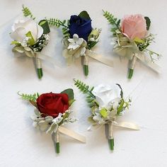 four different colored boutions with white and red flowers on them are arranged in a row