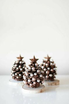 three small pinecone trees sitting on top of a white table next to each other