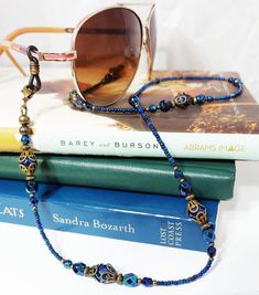 "Vintage inspired Iridescent blue iris Beaded Eyeglass Chain. Variety of faceted Czech glass beads with an AB finish, this gives the beads a rainbow effect. The lanyard is accented with antiqued brass filigree bead caps create a vintage look. I completed the lanyard with Czech glass seed beads with eyeglass connectors. Show off your unique sense of style when you wear this wonderful eyeglass chain. FEATURES > Total length 28\", may be adjusted upon request > Your choice of eyeglass connectors, skinny arm or wide arm. > To ensure long lasting wear I use professional quality beading wire (49 strand). The beading wire is very strong and flexible, providing a soft drape and it lays softly on the neck for maximum. Wire guardians are incorporated to protect wire from wear. The wire is double cri Beaded Eyeglass Chain, Brass Filigree, Blue Iris, Iridescent Blue, Eyeglass Chain, Glasses Chain, Beading Wire, Metallic Blue, Blue Vintage