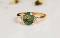 a close up of a ring with a green stone in the middle and three small diamonds around it