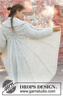 a woman wearing a white coat and holding her arms out to the side, while standing in front of a brick wall