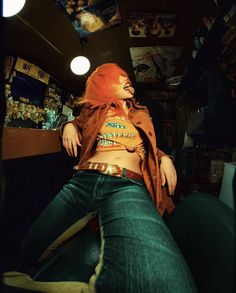 a woman with red hair is sitting in a bar wearing green pants and a brown jacket