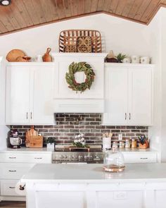 a kitchen with white cabinets and a wreath on the wall