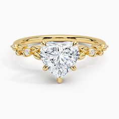 a yellow gold engagement ring with a heart shaped diamond in the center and side stones