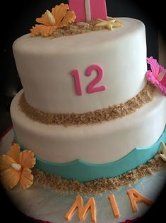 a two tiered cake decorated with flowers and sand