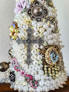 a christmas tree made out of pearls and other beads with a cross on the top