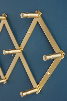 two gold metal racks on a blue wall with white knobs and holes in the middle