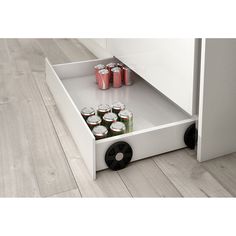 an open drawer on the side of a white cabinet with cans and cans in it