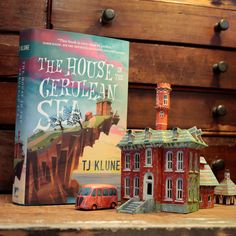 a book sitting on top of a wooden table next to a toy bus and building