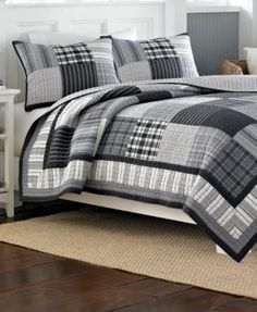 a bed in a room with a plaid comforter and pillows on top of it