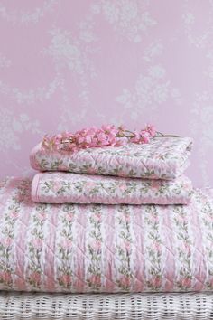 pink and white bedding with flowers on the top, next to a wicker basket