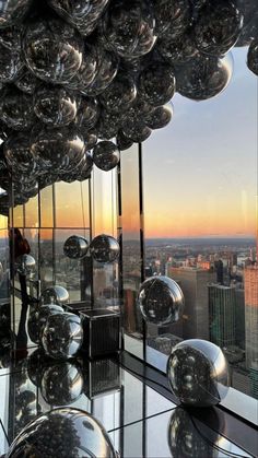 a room with lots of shiny balls hanging from it's ceiling and windows overlooking the city