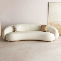 a white couch sitting on top of a hard wood floor next to a painting and lamp