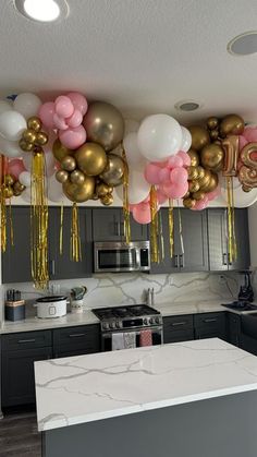 balloons and streamers are hanging from the ceiling in this modern kitchen with marble countertops