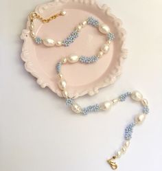 a plate with a necklace on it next to a beaded necklace and a chain