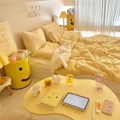 a bed room with a neatly made bed next to a yellow coffee table and laptop