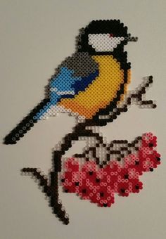 a colorful bird sitting on top of a piece of art made from perler beads