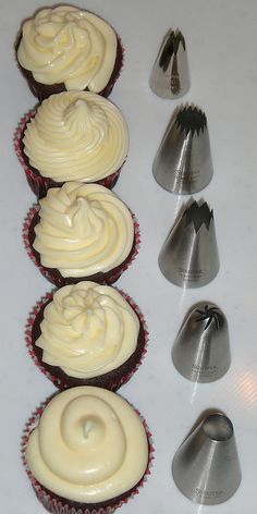 four cupcakes with white frosting next to each other