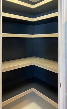 an empty closet with blue walls and wooden shelves