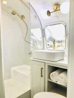 a white toilet sitting next to a sink in a bathroom under a mirror and lights