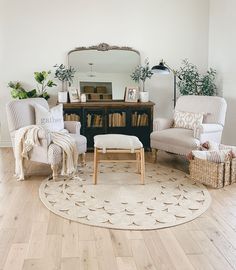 a living room with two chairs and a rug in front of a mirror on the wall